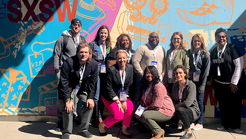 A group gathers for a photo at SXSWEDU 2018 in front of wall art in Austin, Texas.
