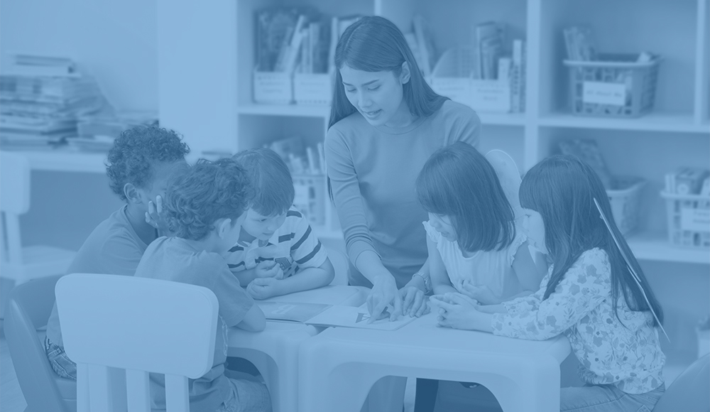 early educator teaches a group of students gathered around a table