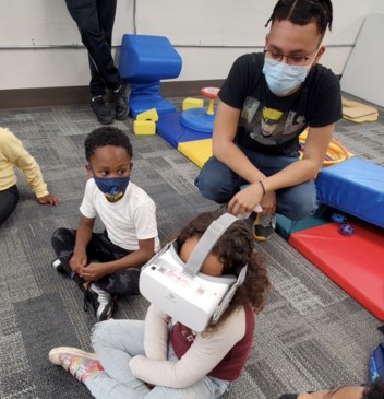A young girl wears a virtual reality (VR) headset in an elementary school classroom.