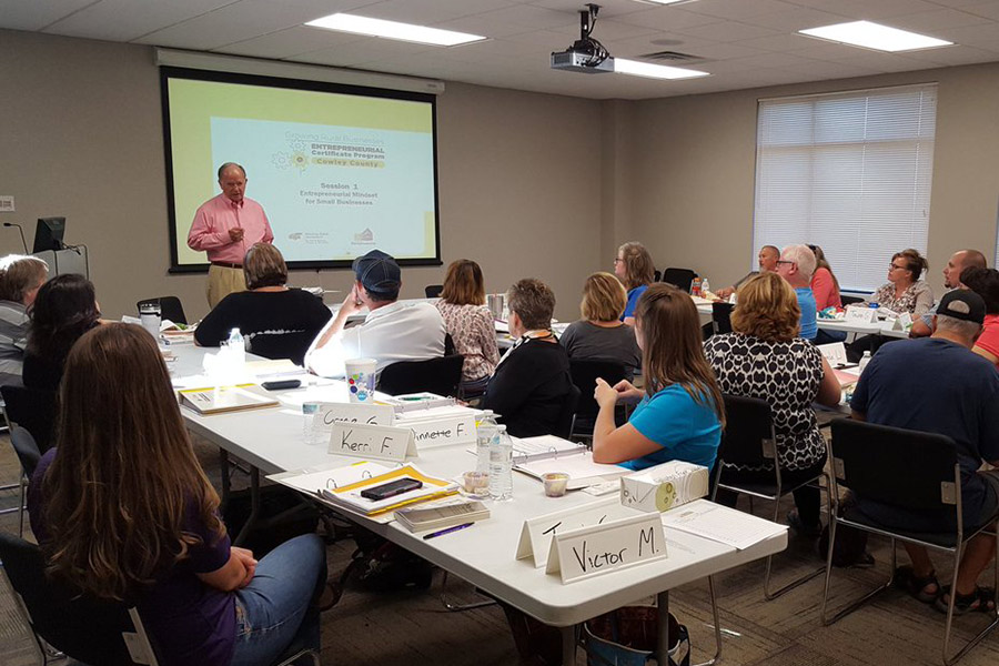 A facilitator stands in front of a room full of participants at a NetWork Kansas E-Community Growing Rural Businesses event.