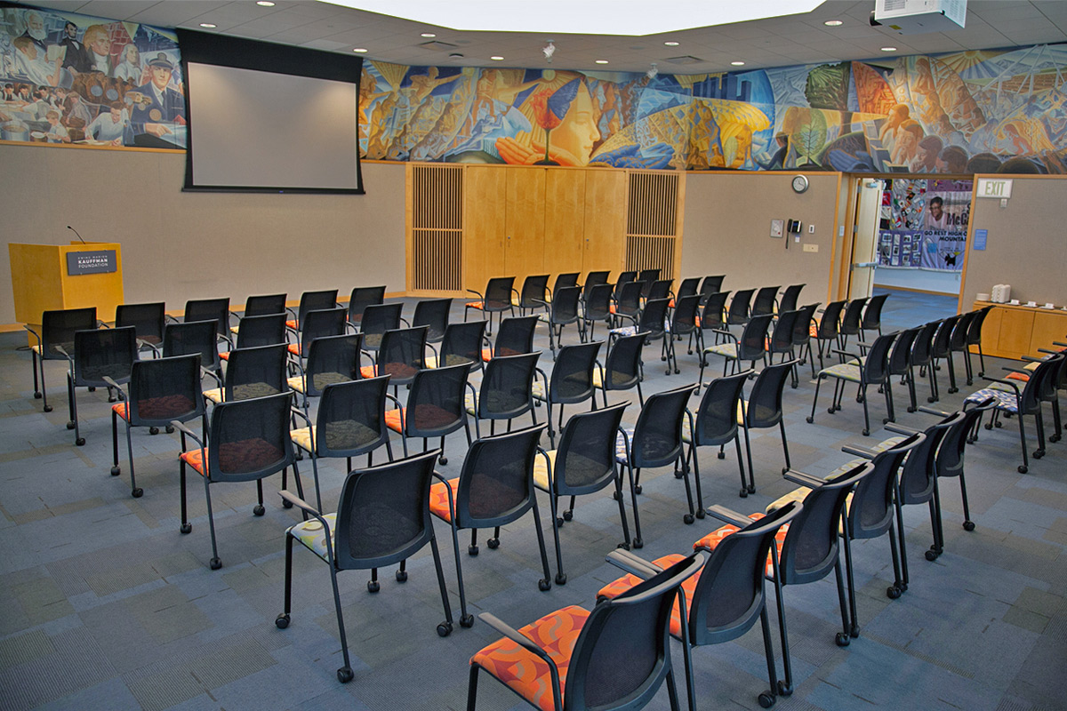 A larger conference room featuring seats for 72 people, a standing podium at the front, and a multi-wall mural featuring iconic sights from Kansas City.