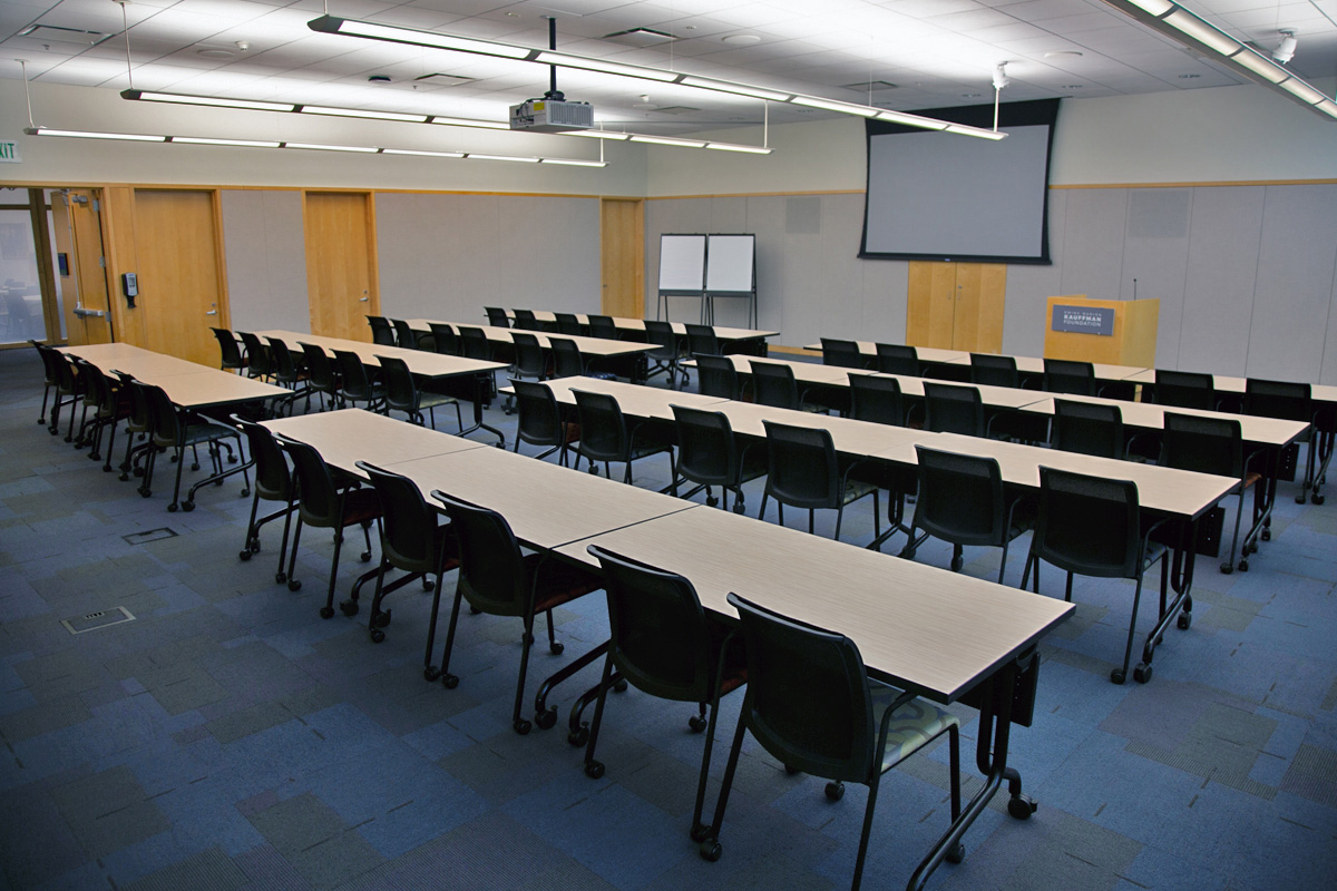 A larger conference room with several tables, with enough seats for 48 people. A standing podium is at the front of the room.