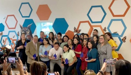 A large group of people receive awards from Revolucion Educativa and pose for a photo holding them. 