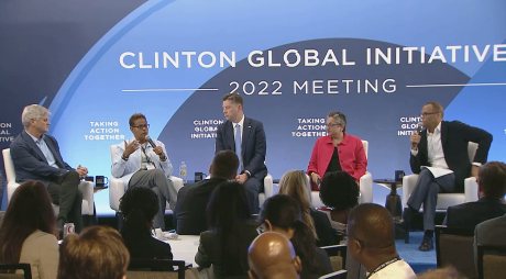 A panel of five entrepreneurship leaders sit on a stage in front of a live audience answering questions. Behind them is a screen that reads "Clinton Global Initiative, 2022 Meeting"