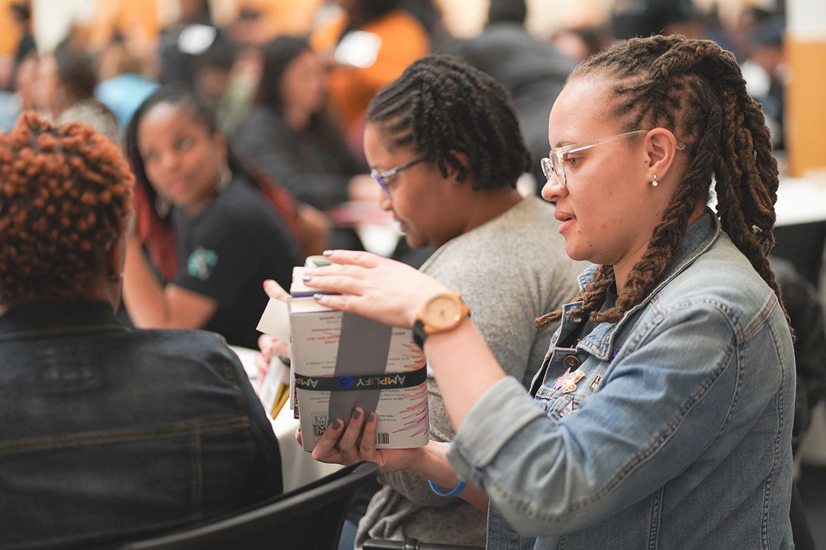 An Amplify attendee examines a stack of books, which was given to attendees as part of the conference.