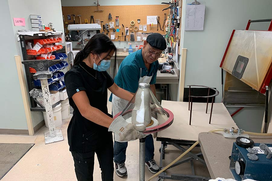 A mentor helps a student during an internship project inside a lab.