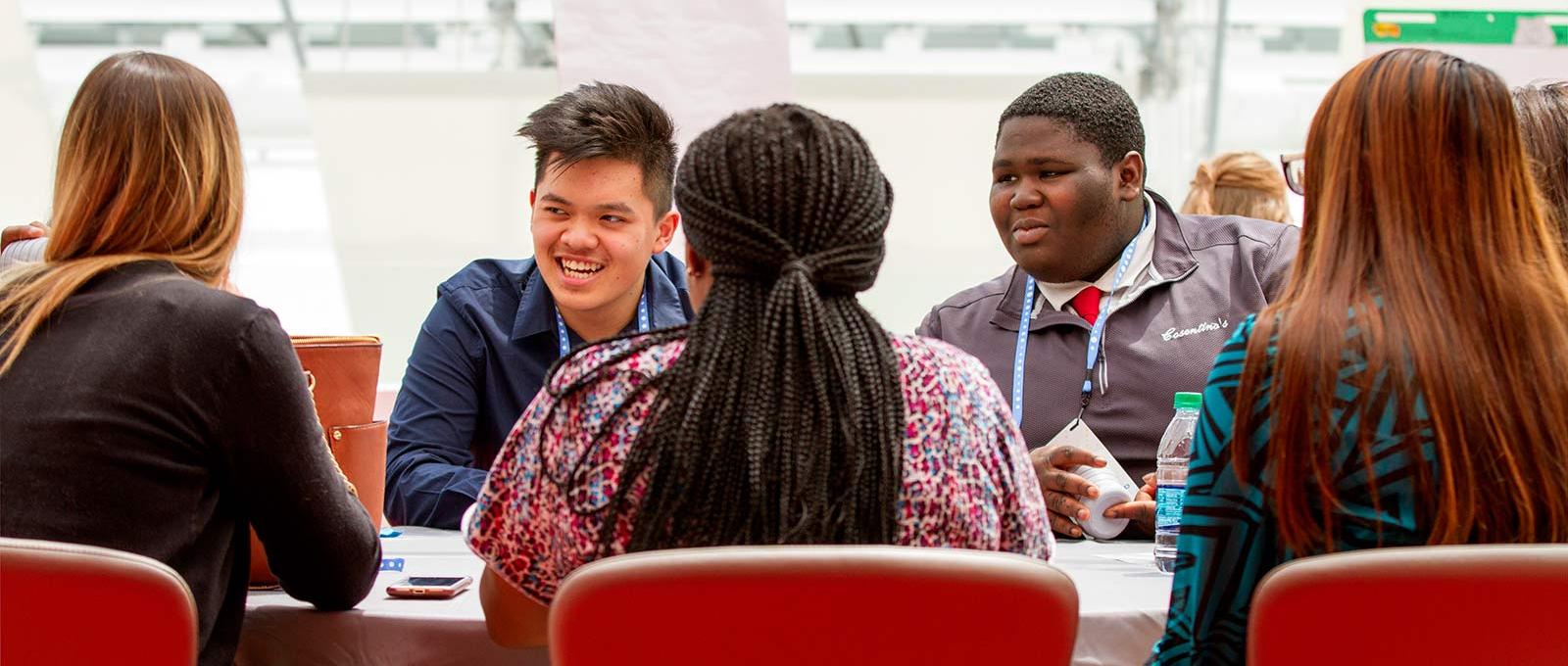 A group of students sit around a table at a learning conference.