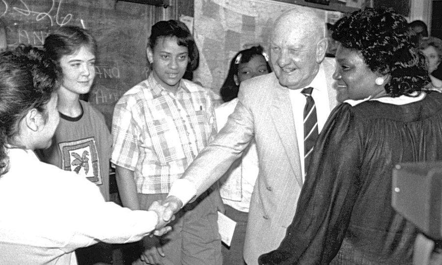 Mr. Kauffman shakes hands with a student in a classroom.