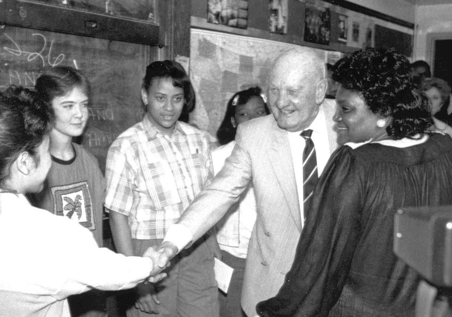 Mr. Kauffman shakes hands with a student in a classroom.