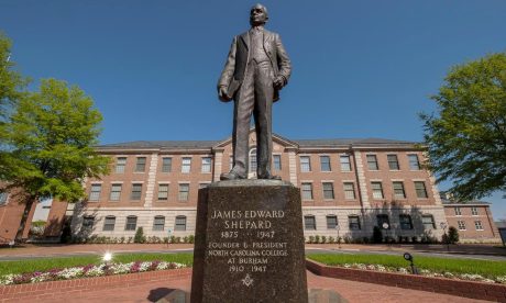 A statue of a man in front of a brick college building with an inscription that reads: "James Edward Shepard 1875-1947, Founder & President, North Carolina College at Durham 1910-1947"