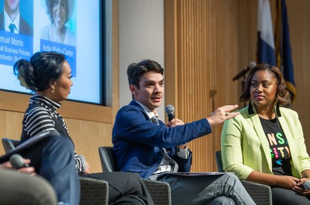 Panelist and entrepreneur Samuel Morris speaks into a microphone and motions to the audience.