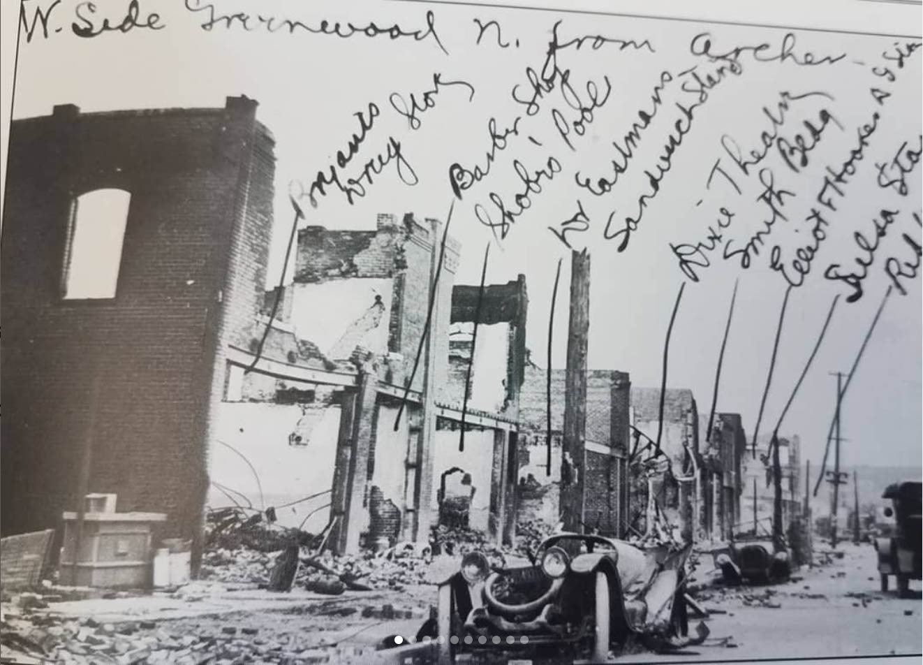 A photograph of the devastation that occurred to Black Wall Street on the north side of Greenwood Avenue in Tulsa, Oklahoma, with the handwritten names of the businesses that were destroyed.