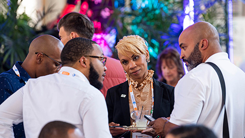 Four people of color engage in conversation, with other attendees in different conversations around them, at the 2019 ESHIP Summit conference in Kansas City, Missouri.