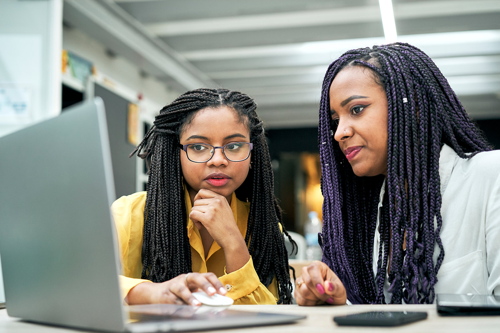 Two young people sit in front of a shared laptop.
