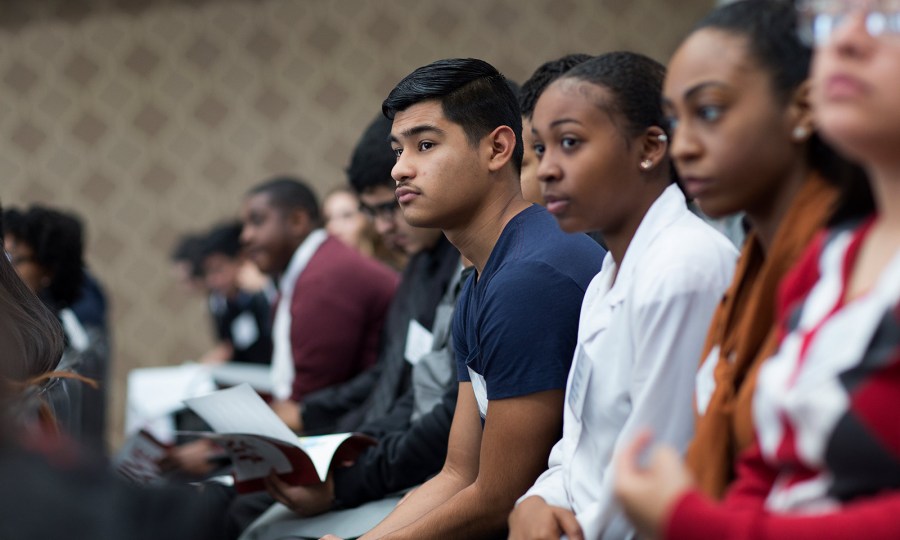 A group of young people sit side-by-side.