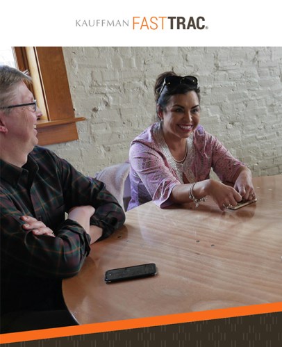 An entrepreneur sits at a round table with another person listening to them share their story.