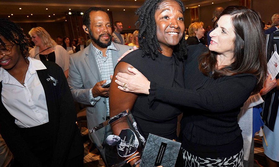 Fahteema Parrish, president and founder of Parrish & Sons Construction, holds the Mr. K Award she received at the KC Chamber Small Business Celebration, and is embraced by Lisa Ginter, CEO of Community America Credit Union.