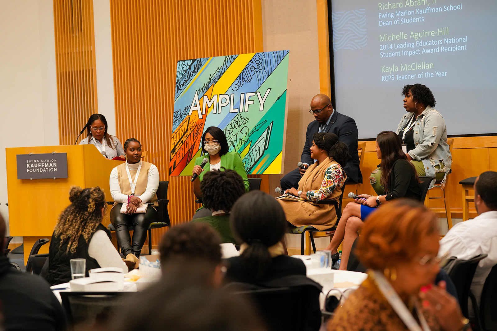 A group of six panelists address a group of attendees.