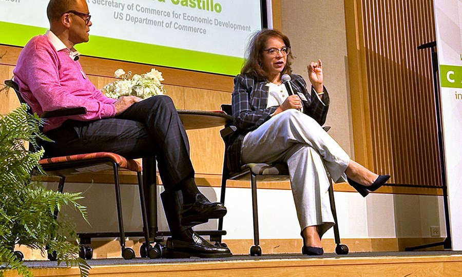 Alejandra Y. Castillo, Assistant Secretary of Commerce for Economic Development with the U.S. Department of Commerce, speaks into a microphone on stage at the Capital Innovation Summit. Philip Gaskin, vice president of Entrepreneurship with the Ewing Marion Kauffman Foundation, sits beside her on stage.
