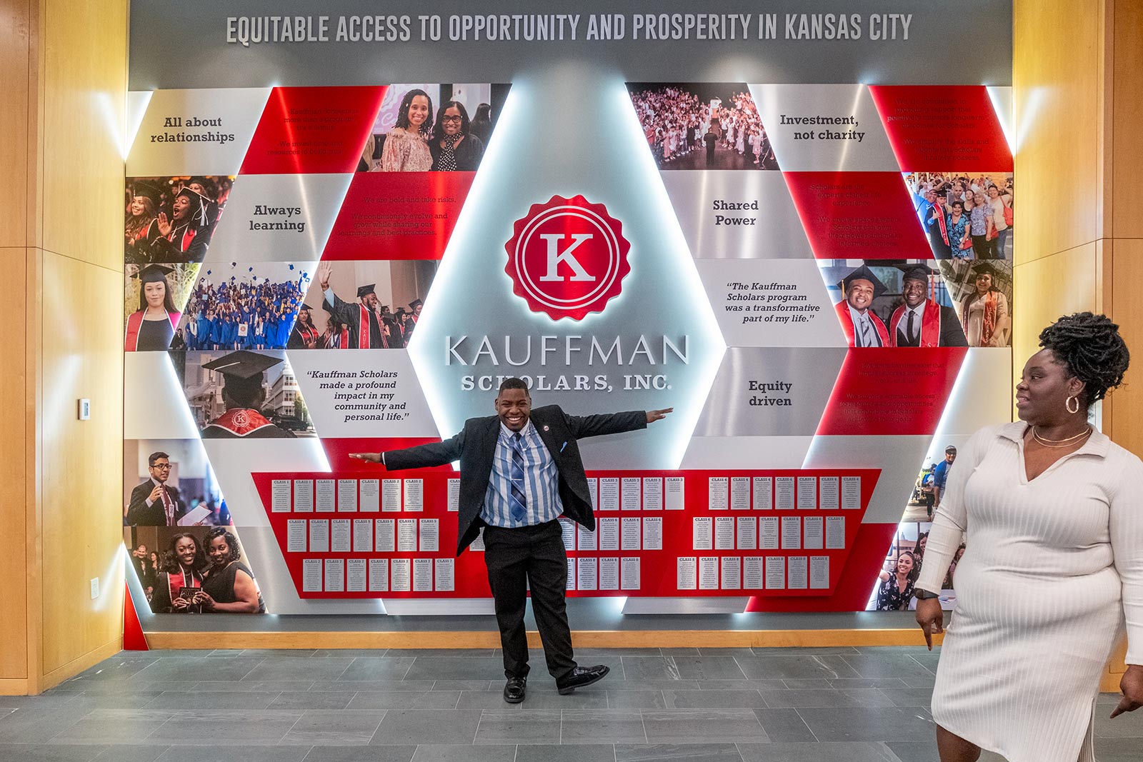A Kauffman Scholars alum poses in front of the KSI Legacy Wall inside the Kauffman Foundation Conference Center.