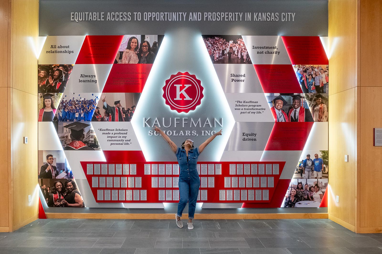 A Kauffman Scholars alum poses in front of the KSI Legacy Wall inside the Kauffman Foundation Conference Center.