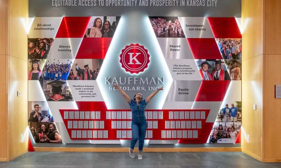 A Kauffman Scholars alum poses in front of the KSI Legacy Wall inside the Kauffman Foundation Conference Center.