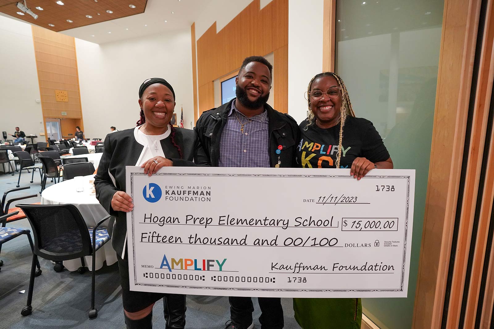 Amplify KC attendees and educators pose with a life-sized check awarded to them during the EduTank Pitch Event