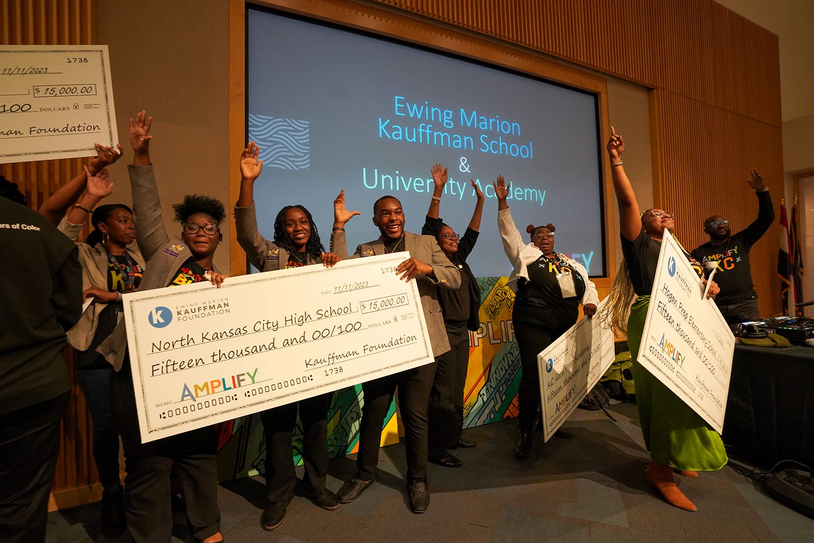 Educators and students from Brookside Charter School, Hogan Preparatory Academy, Kansas City Girls Preparatory Academy, and North Kansas City High School celebrate with life-sized checks at the 2023 Amplify Conference.