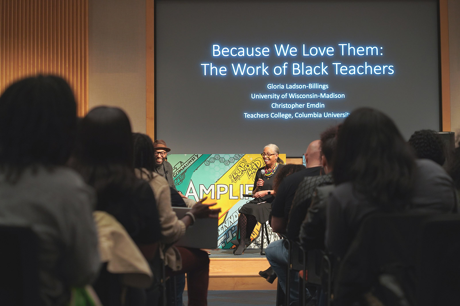 Dr. Christopher Emdin and Gloria Ladson-Billings facilitate a session at Amplify 2020. The screen behind them reads: "Because We Love Them: The Work of Black Teachers."