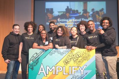 Amplify attendees pose for photo behind Amplify sign