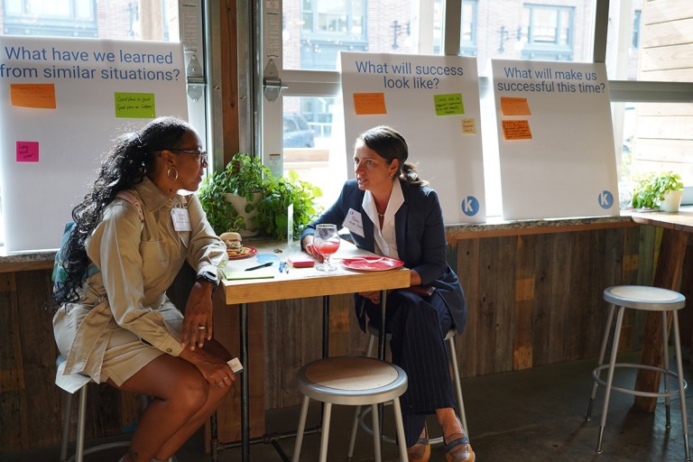 Two grantees in conversation at a high top table
