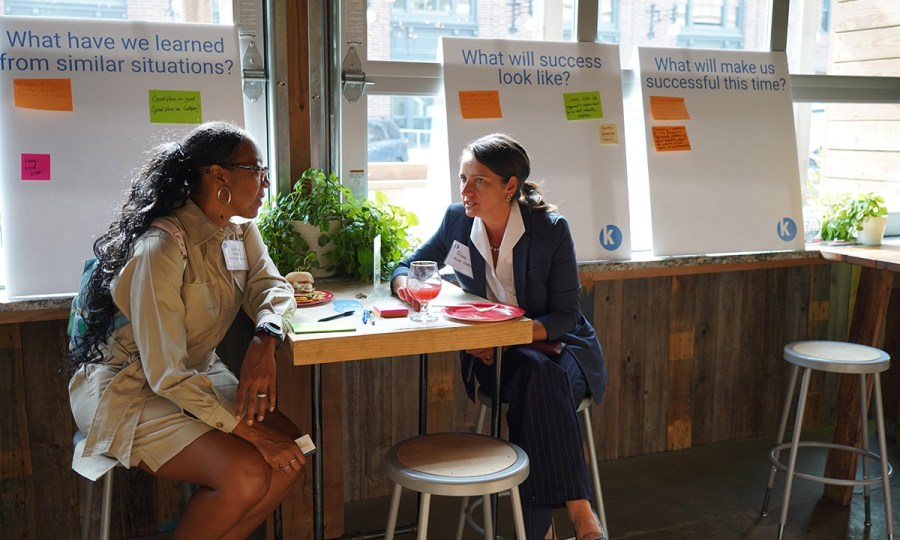 Two grantees in conversation at a high top table