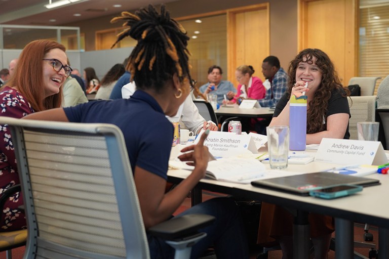 Project grantees laugh in conversation at a long table