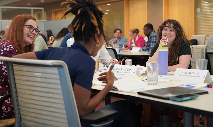 Project grantees laugh in conversation at a long table