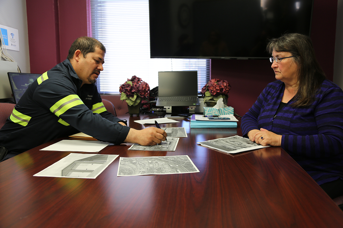 Two people sit at a table with documents in between them.