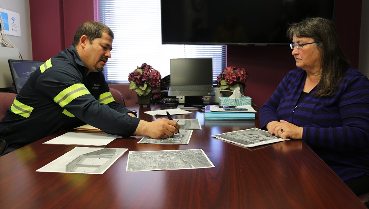 Two people sit at a table with documents in between them.