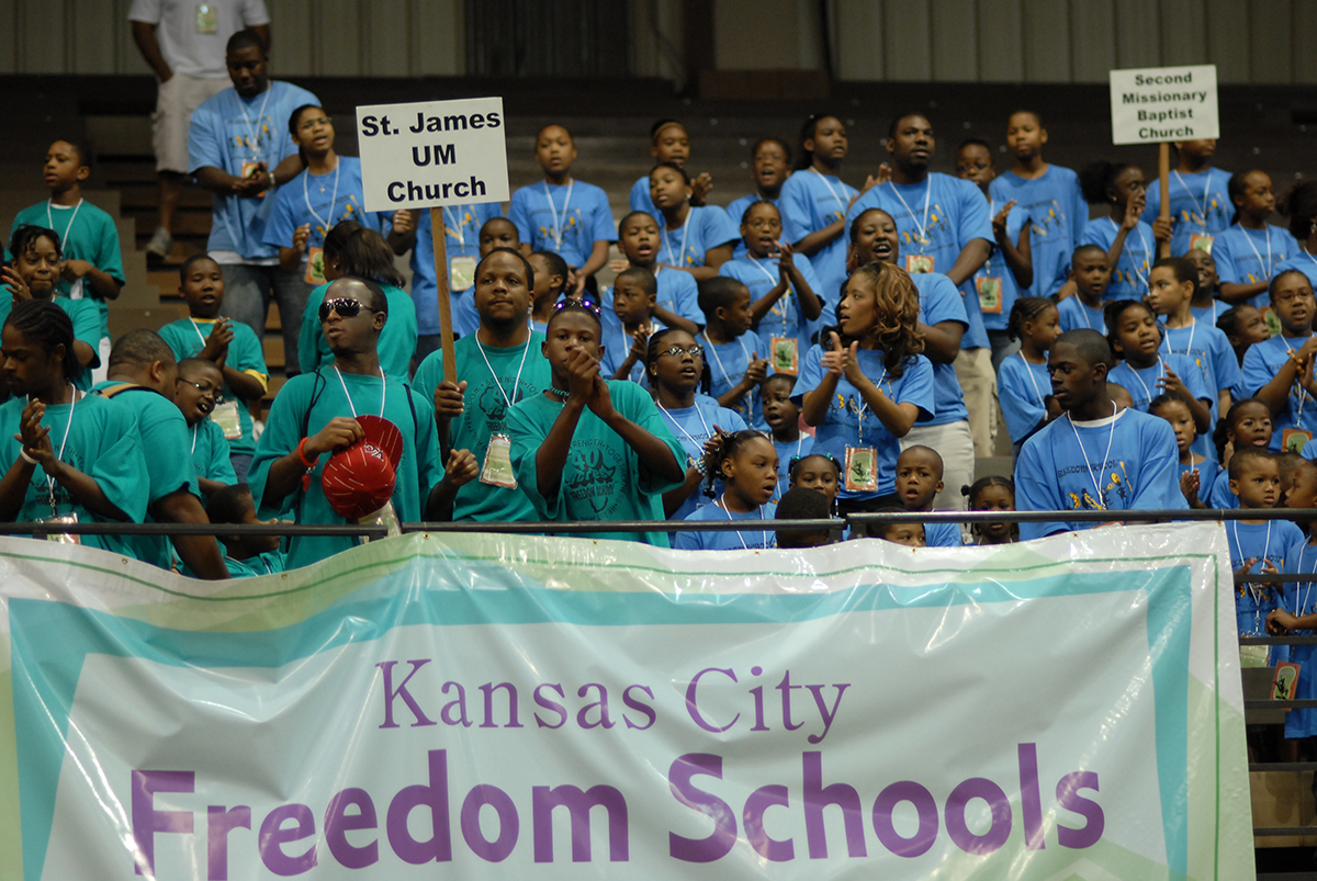 A group of students stand behind a banner that reads "Kansas City Freedom Schools"