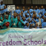 A group of students stand behind a banner that reads "Kansas City Freedom Schools"