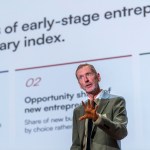 A presenter stands in front of a projected screen sharing insights from the Kauffman Indicators of Early-Stage Entrepreneurship