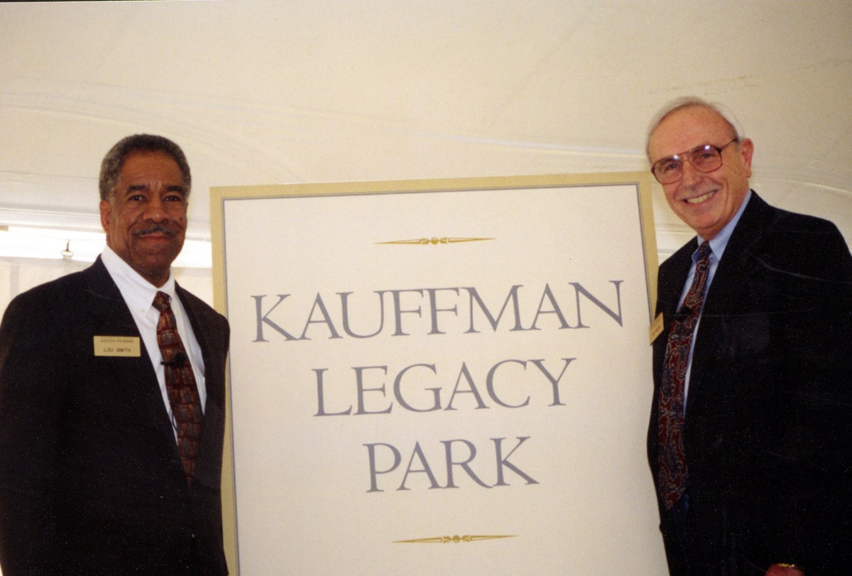 Lou Smith stands next to a sign that reads Kauffman Legacy Park